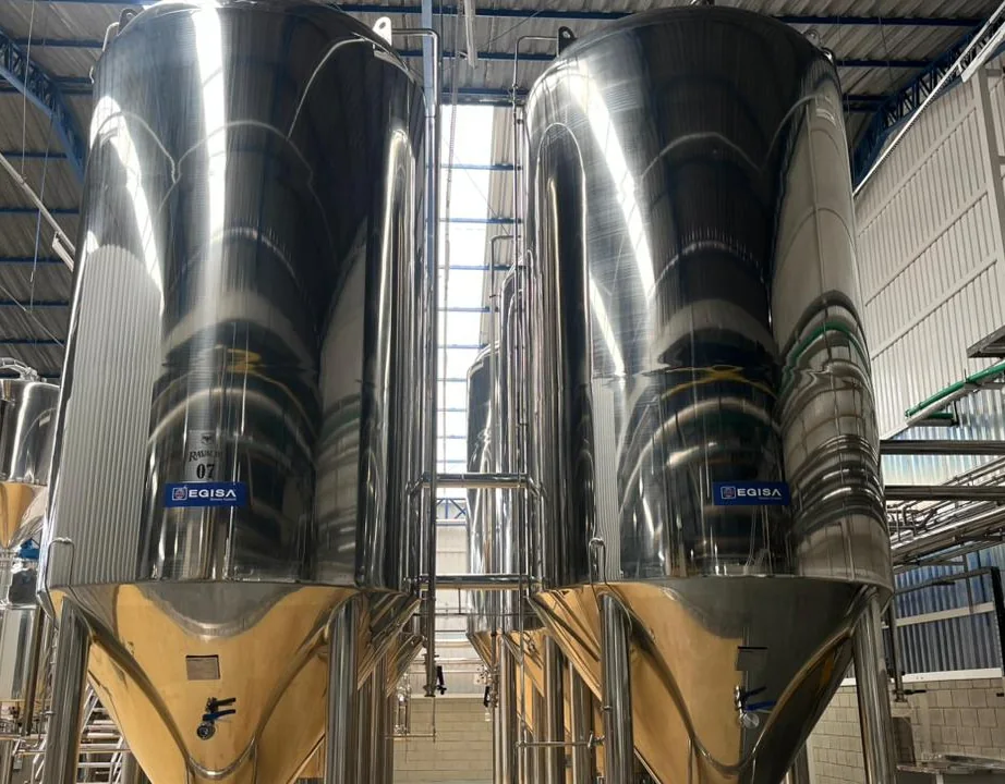 Sala de fermentação da Cervejaria Ravache: tanques de aço inox em fuga de perspectiva